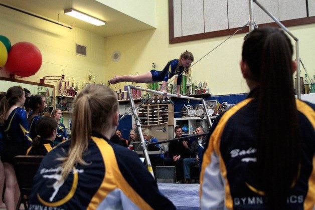 The Spartans watch a teammate compete in the bars during action against Holy Names.