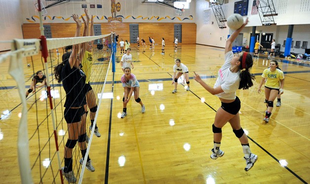 (L-R) Sophomore Erin Kinney and co-captain Kat Frickleton go up to block Maddy Stevenson’s hit as co-captain Nina Mutty (far right) looks on at practice Tuesday.  Frickleton and juniors Mutty