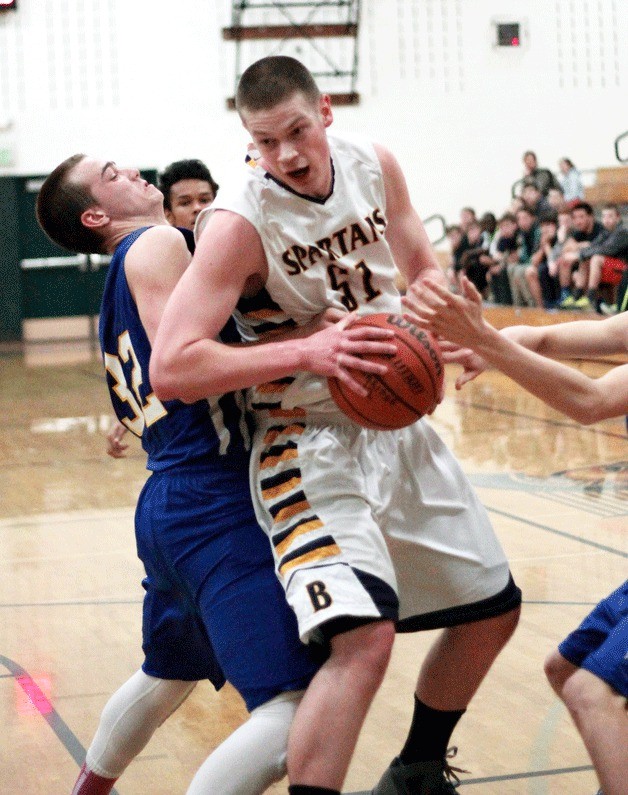 Bainbridge junior wing/post Oskar Dieterich plows through the defensive efforts of W. Seattle during the Spartan home game against the Wildcats Tuesday