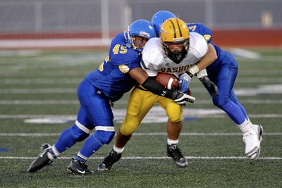 Two Bainbridge players attempt to tackle the ball carrier.