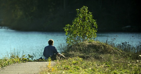 Michael Ellis sits on the concrete edge of a walkway out to Eagle Harbor at Strawberry Plant Park