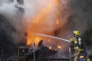 A Bainbridge firefighter douses flames at a home on Skogen Lane Jan. 8.