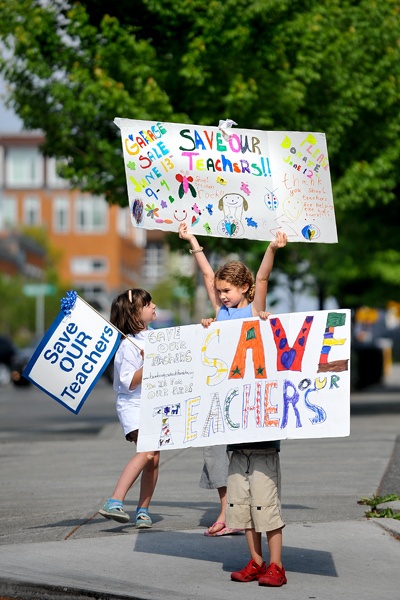 Young 'Save our Teachers' volunteers wave signs on Winslow Way last week.