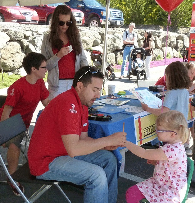 A youngster gets her hand painted by KiDiMu volunteer Gabe Carbajal at last year's birthday bash.