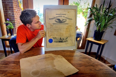 Rudi Pettersen holds up an official document signed by U.S. President William McKinley in 1900. A document signed by Theodore Roosevelt rests on the table. Both documents were found in the family garage.