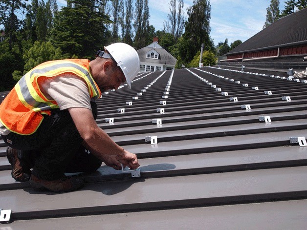 Jason Duensing of Sunergy installs solar panel mounting gear on the roof of city hall.