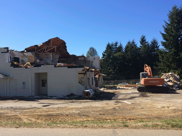 Demolition of the two-story building that once housed real-estate offices at the corner of Highway 305 and High School Road began Friday.