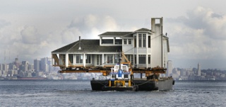 A tugboat maneuvers a barge carrying a 3