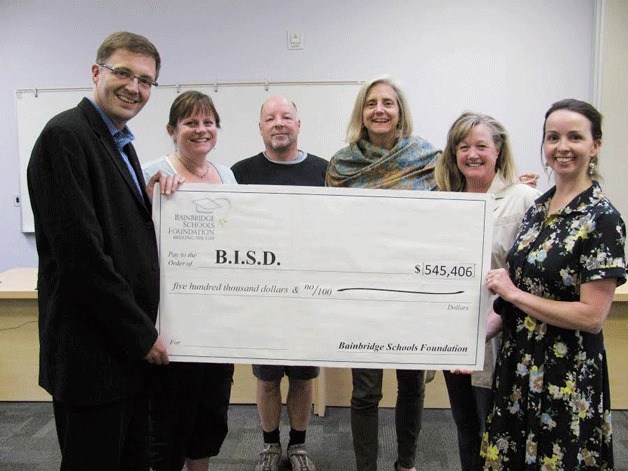 Bainbridge Schools Foundation executive director Mairead Shutt (far right) presents the nonprofit’s annual gift to Associate Superintendent Peter Bang-Knudsen and school board members Sheila Jakubik