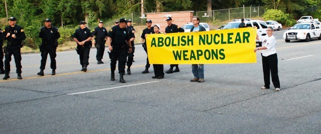 Demonstrators from the Ground Zero Center for Nonviolent Action hold a banner while blocking traffic at Naval Base Kitsap on Monday to mark the anniversary of the Hiroshima bombing.