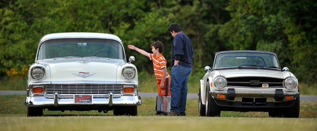 Islanders Henry Vandersluis and automobile designer Raffi Minasian examine a 1956 Chevrolet (left) and 1970s Triumph TR6 at the weekly Cruise-In at Bainbridge First Baptist Church on Madison Avenue. Every Tuesday from June through August