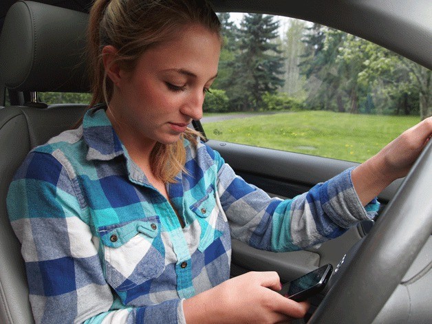 With one hand on the wheel and the other on her phone