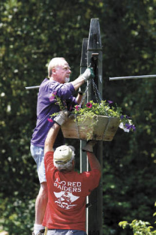 Volunteers Ron Williamson and George Moser joined about a dozen other people Monday afternoon to hand over 60 flower baskets along Winslow Way.