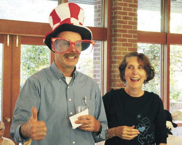 Jane Allan lends her goofy hat and glasses to John DeMeyer from the parks district as part of the many light-hearted high jinx at a celebration commemorating her 13-year service as director of the Bainbridge Island Senior Community Center.