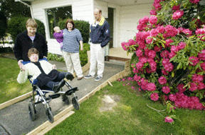 Caregiver Chris Powers (left) helps Brittany Deits cross the work area where a ramp for disabled access is being built at Stephens House. Tiffany Kleiven