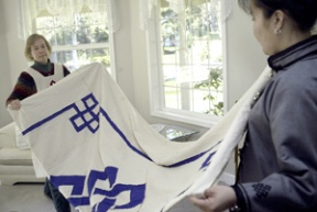 Maggie Ball (left) helps Selenge Tserendash unfurl a quilt made by women at the New Way Life Mongolian Quilting Center.