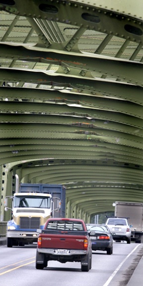 Motorists pass across the Agate Passage Bridge beneath a series of girders badly damaged by an errant crane last April. The state Department of Transportation plans to repair the damage beginning March 4