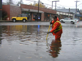 A public works employee clears a drain in front of Cafe Nola. The system was fouled by leaves and overwhelmed by water from Madison Ave.