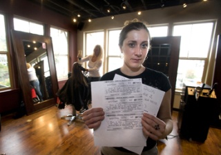 Carisa Crone holds copies of fake postal money orders that were sent to an employee at Studio M Salon & Spa.