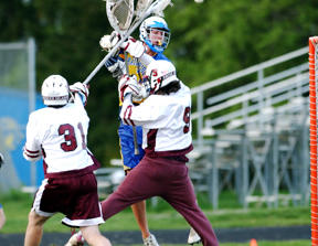 Bainbridge’s Joe Picha (center) is challenged by Mercer Island’s Andrew Vincent and goalkeeper Jereme Raquepau as he makes a leaping shot Tuesday evening at BHS. The Spartans beat the Islanders 11-7 to remain undefeated on the season.