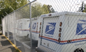 Mail delivery trucks sit behind a newly constructed security fence.