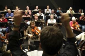 Guest conductor David Upham (foreground) leads the members of the Bainbridge Orchestra in rehearsal on Wednesday night. The ensemble performs April 15 and 16 at the Playhouse.