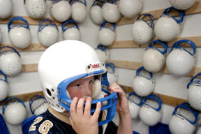 Third-year Pee Wee football player Carson Zajonc fits his helmet after conditioning camp Thursday evening. There are quite a few more helmets to go around this year