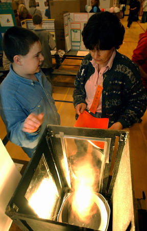 Sakai sixth-grader Jesse Rees (left) explains the workings of his miniature tornado to judge Alison Craig at Thursday’s Science Fair.