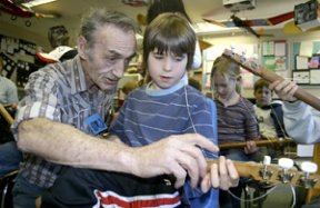 Luthier Andy Mackie shows Trevor Heater how to fret a chord on his “strum stick