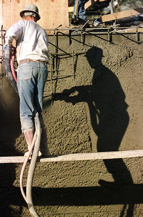 A workman sprays “shotcrete” on a form