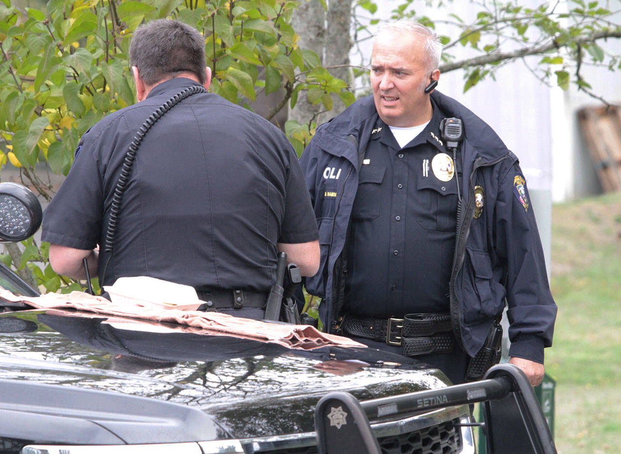 Bainbridge Police Chief Matthew Hamner gets briefed by a Bainbridge police officer at the scene of a death investigation late last year. (Brian Kelly | Bainbridge Island Review)