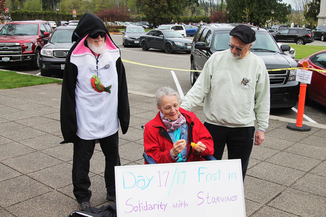 Lanni Johnson breaks her 17-day fast with an orange on Wednesday. She is joined by supporters including Phil Myers from the North Olympic Orca Pod activist group dressed in an orca suit. (Photo by Emma Emperly, WNPA Olympia News Bureau)