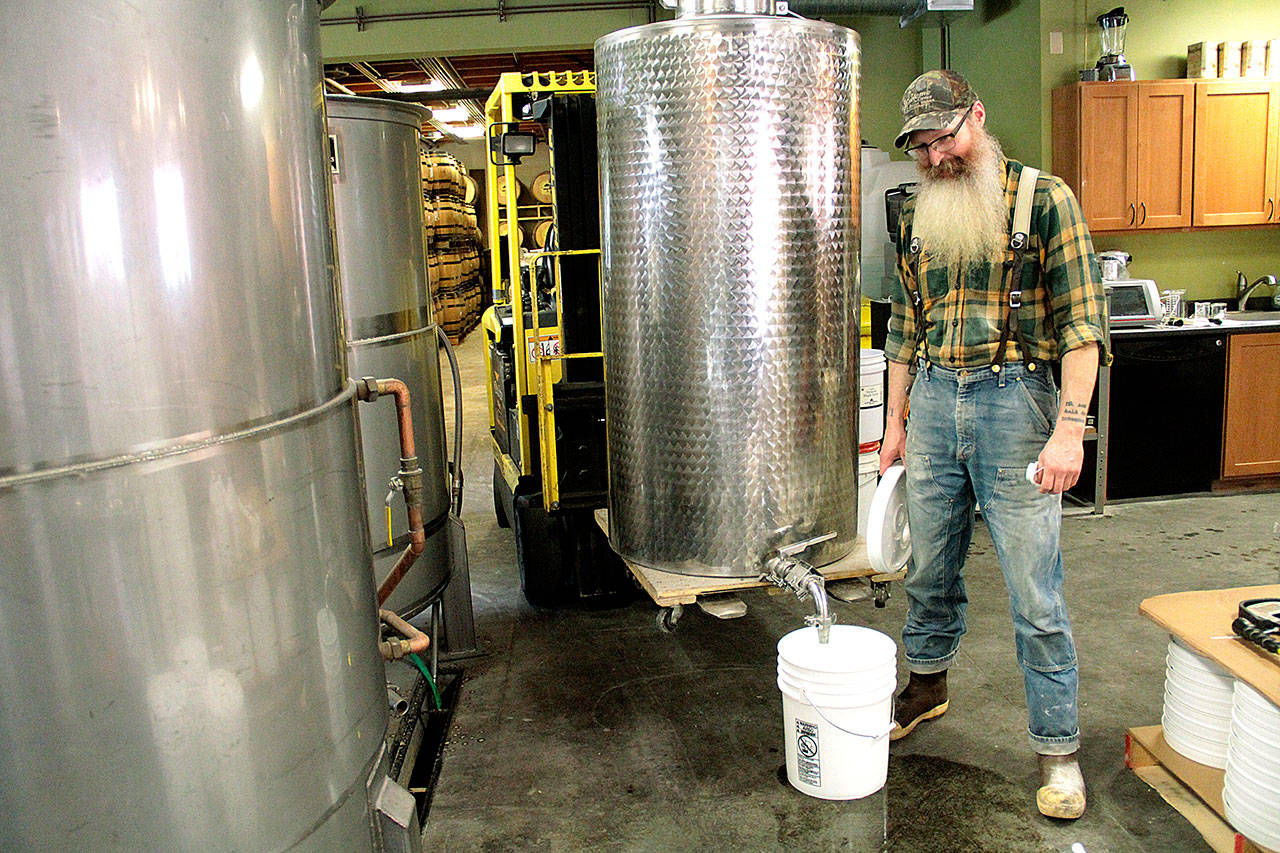 Kevin Barrans, head distiller at Bainbridge Organic Distillers, fills a five-gallon bucket with alcohol taht was made at the Bainbridge business. Buckets of alcohol will be donated to Bainbridge Prepares so it can be made into hand sanitizer. (Brian Kelly | Bainbridge Island Review)