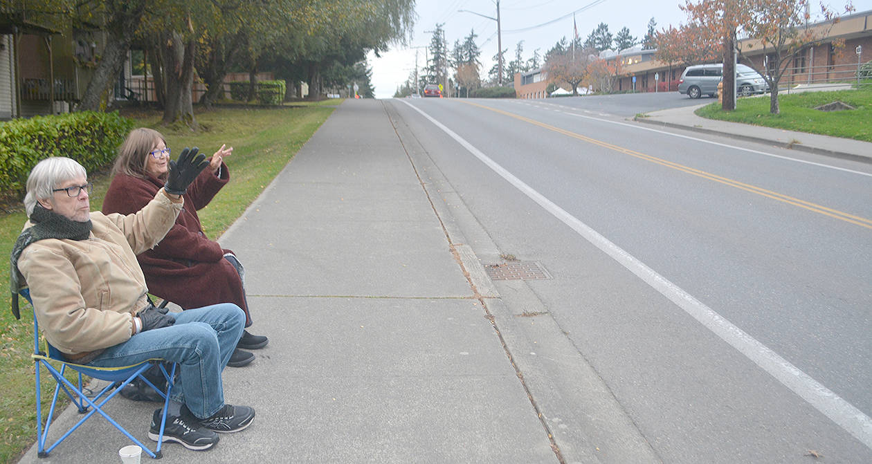 Caregiver Scott McDonald and Vickie Helsi wave to cars as they go by. Steve Powell/Bainbridge Island Review photograph