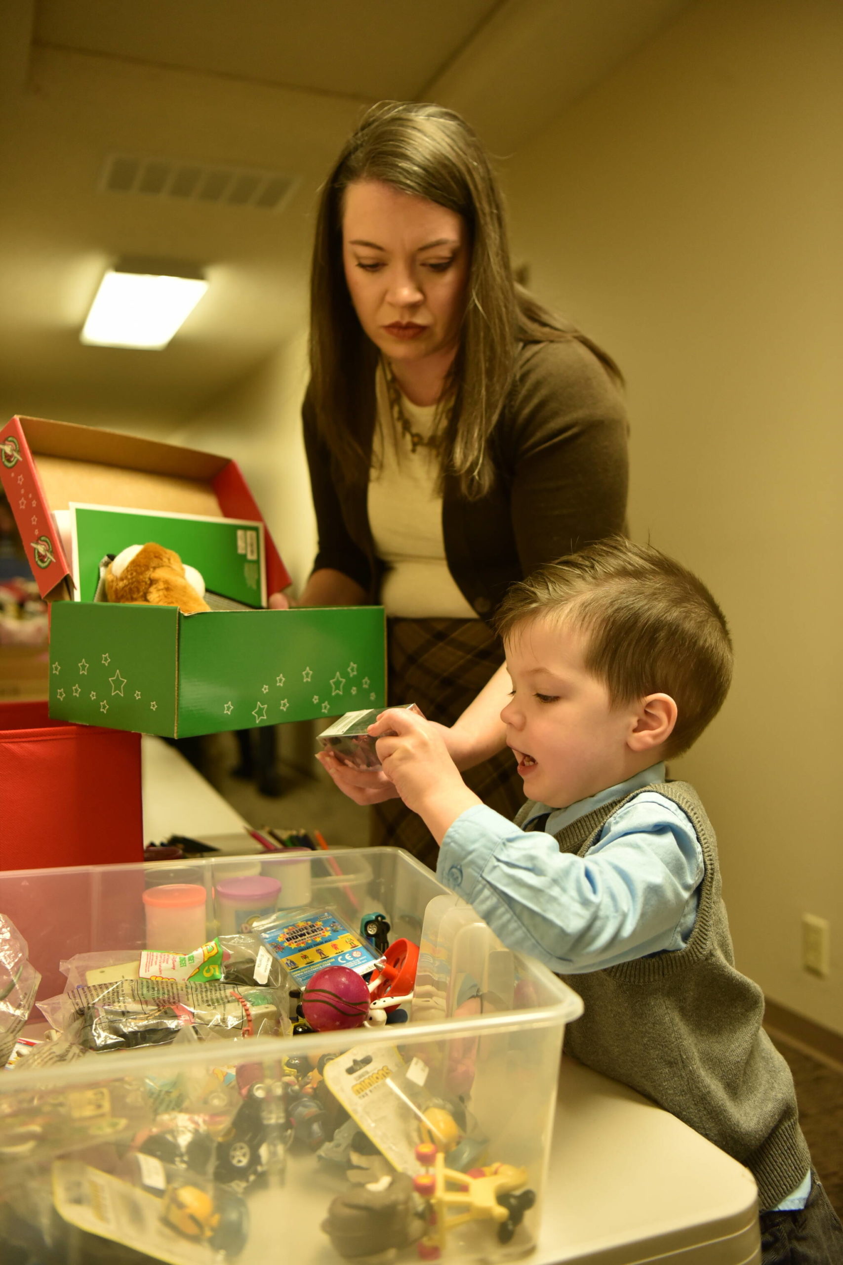 Rachel Garrard helps her son, Luke, 3, fill a box with items for Operation Christmas Child.