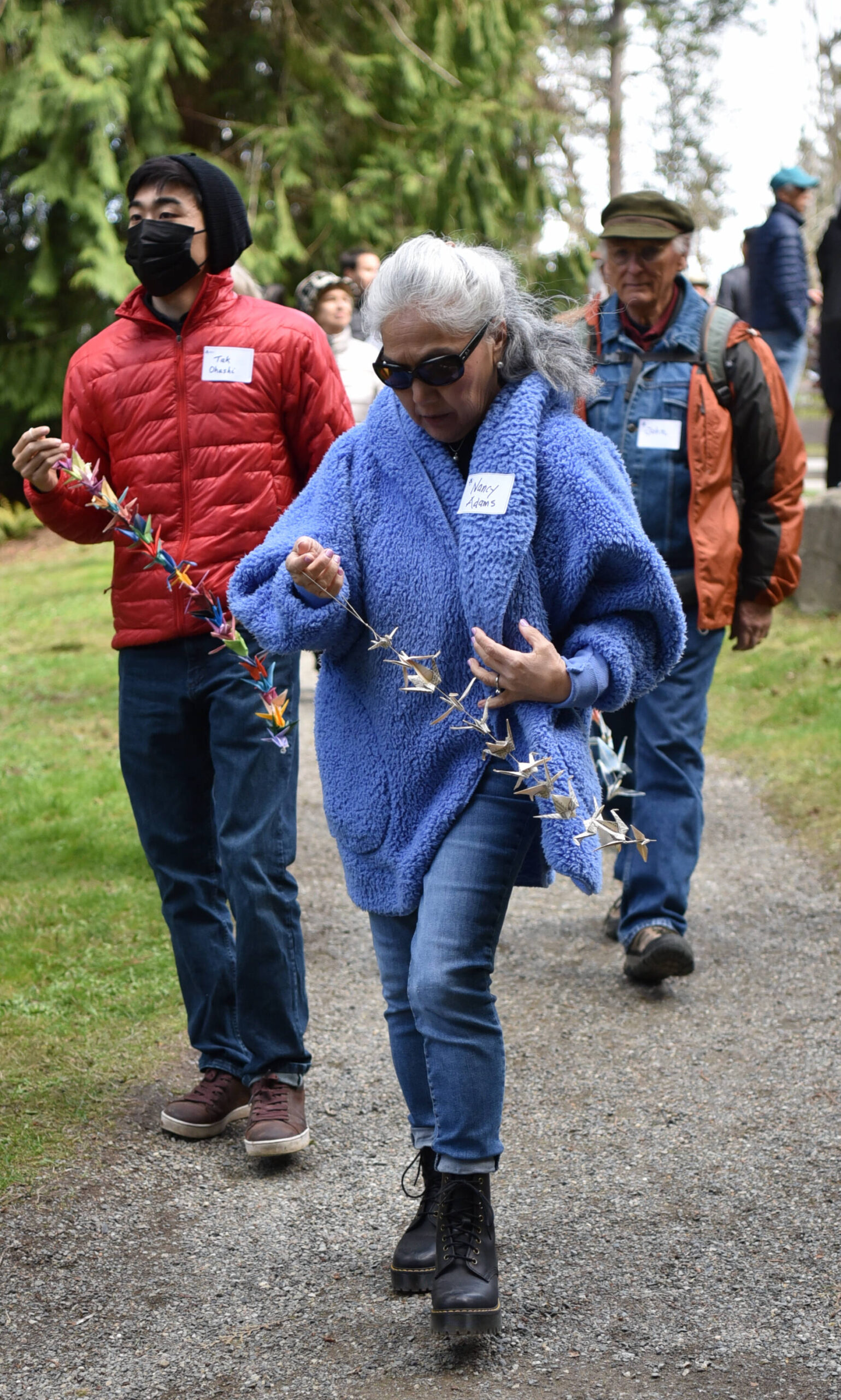 Visitors carry strings of paper cranes to place along the Japanese Exclusion Memorial wall.