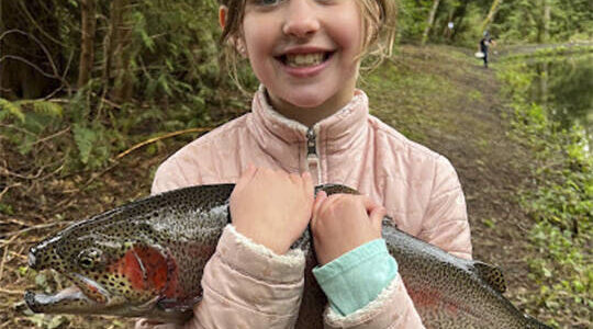 Avery Britt, 9, of Bainbridge Island shows off a fish she caught then released at the BI Sportsmen's Club annual Huck Finn and Becky Thatcher Kids' Fishing Derby. Daniel Britt courtesy photo