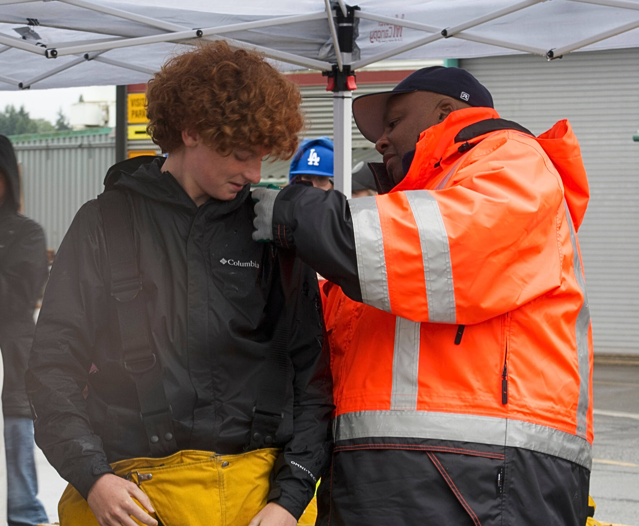 Boatswain Derrick Fant assists student Jack Carrieds don firefighting gear in a demonstration.