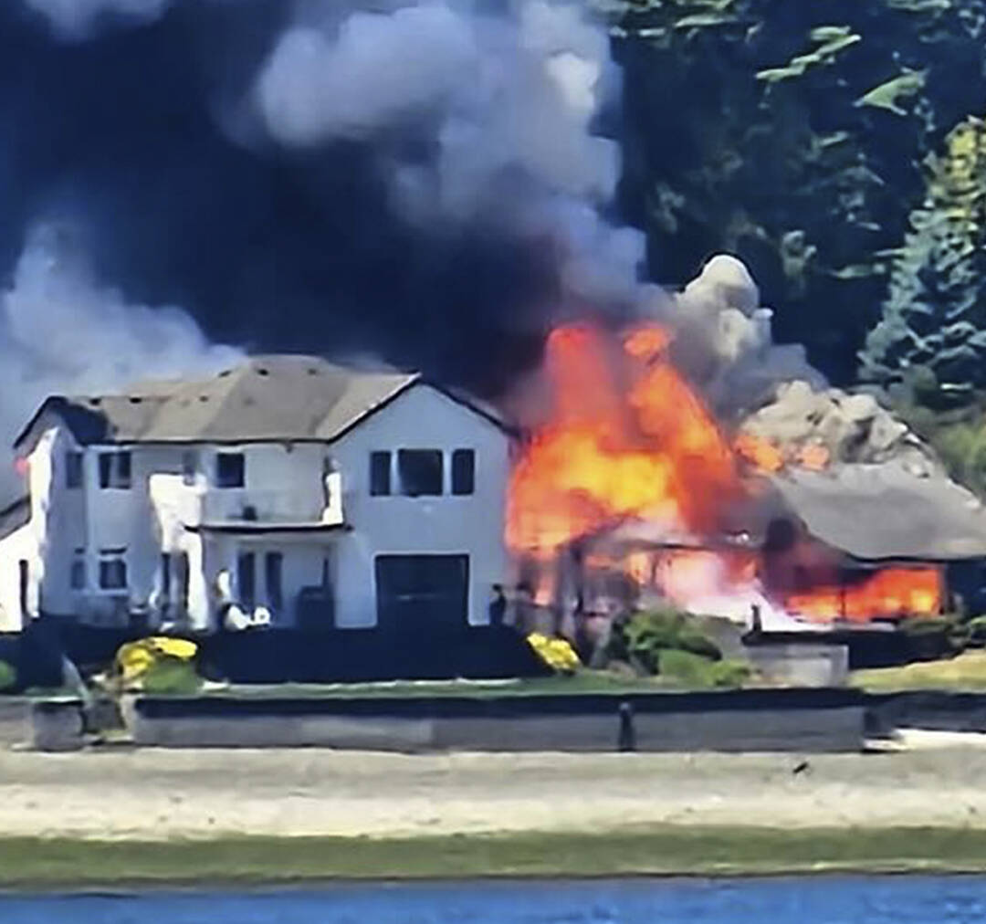 Andrea Powell courtesy photo
Smoke and flames erupt from a three-alarm house fire on Erlands Beach Loop NW.