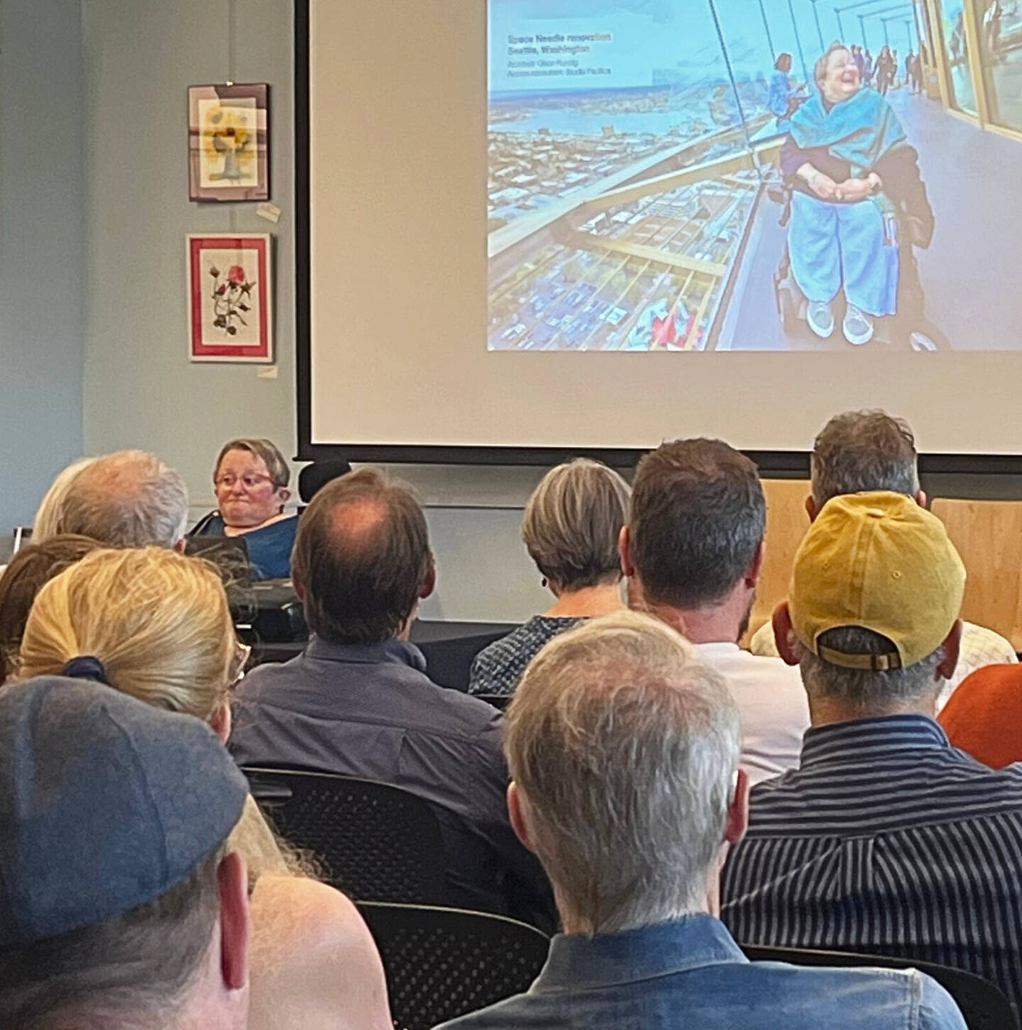 Molly Hetherwick/Kitsap News Group
Karen Braitmayer, left and on screen, talks on Bainbridge about access for people with disabilities.