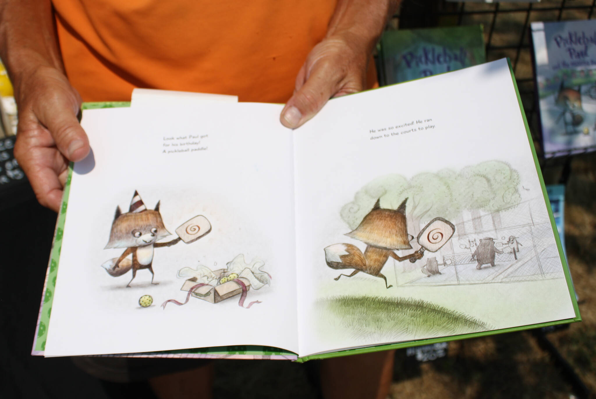 Bill Knopp displays a page from the hit children’s book series, Pickleball Paul, in which a young fox learns valuable life lessons while playing pickleball.