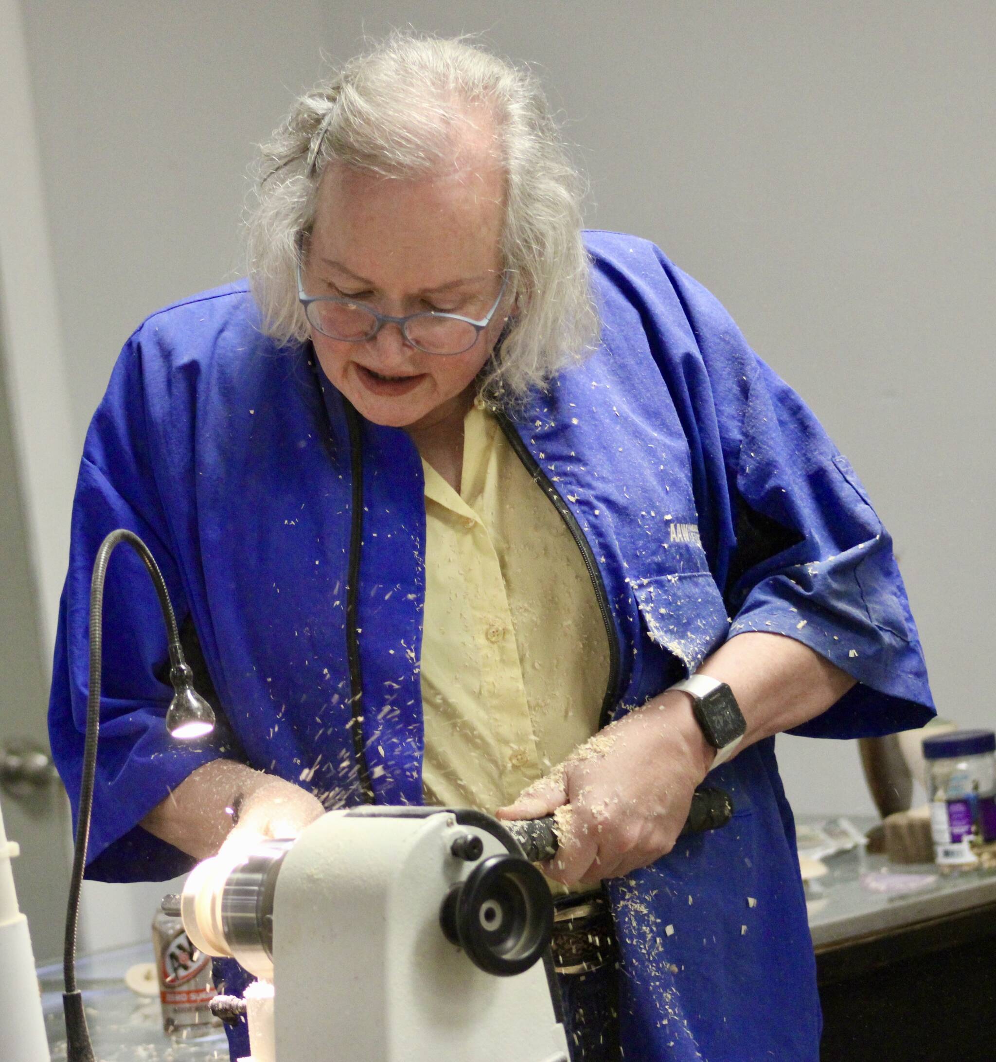 Sawdust goes flying as Robyn Weimer works on a piece of wood in the lathe.