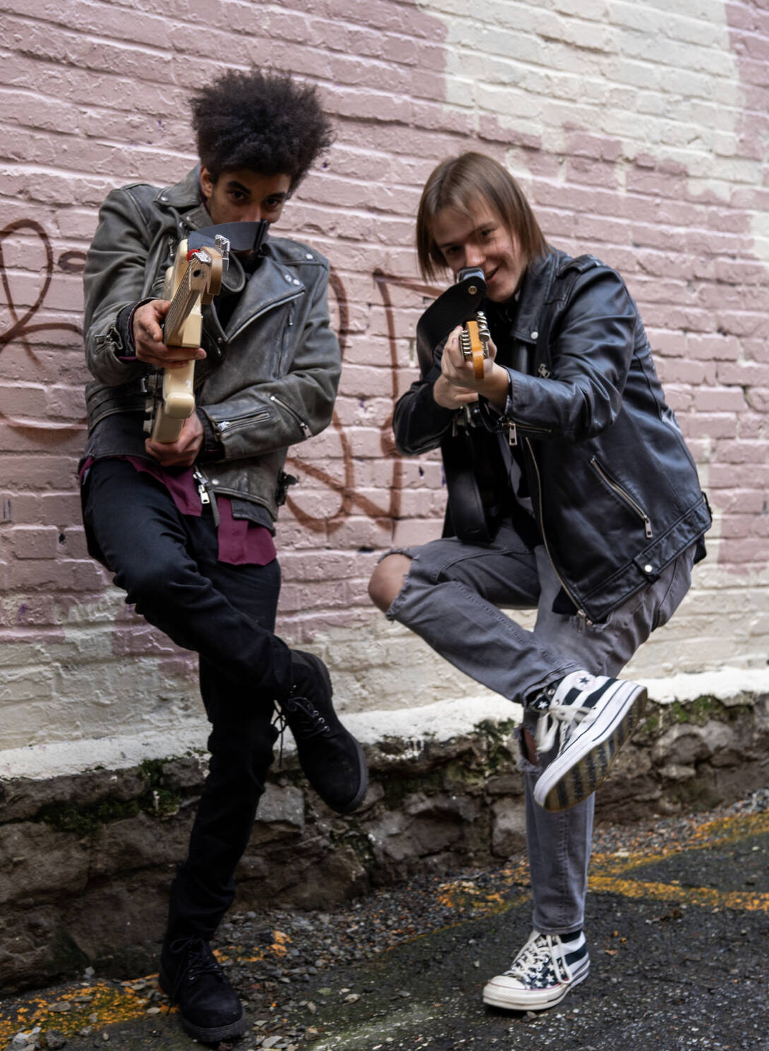 Noah Wossene, left, and Rowan Gano aim their guitars at the camera.