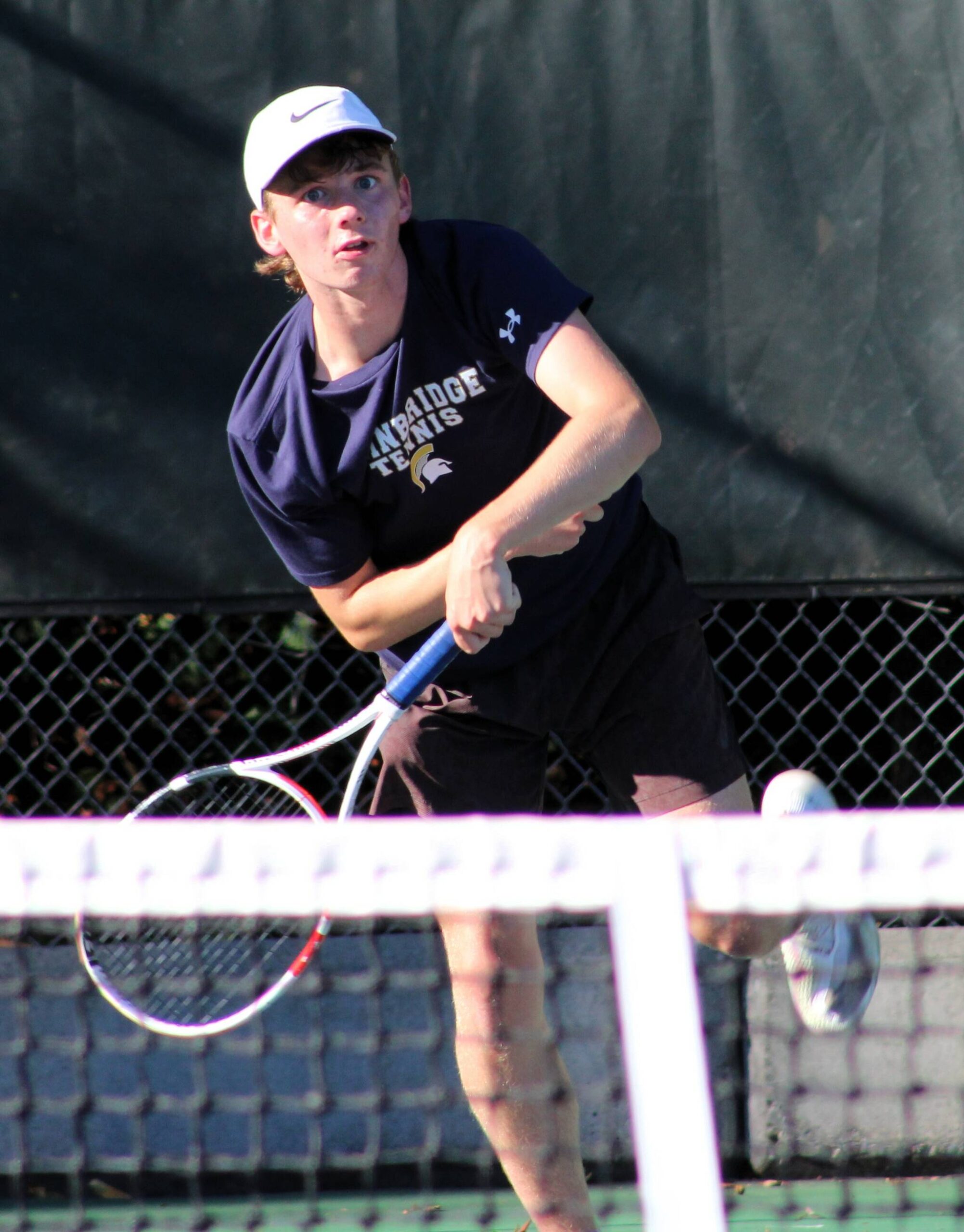 Reed Grandy follows through on a serve during the first set of a doubles match.