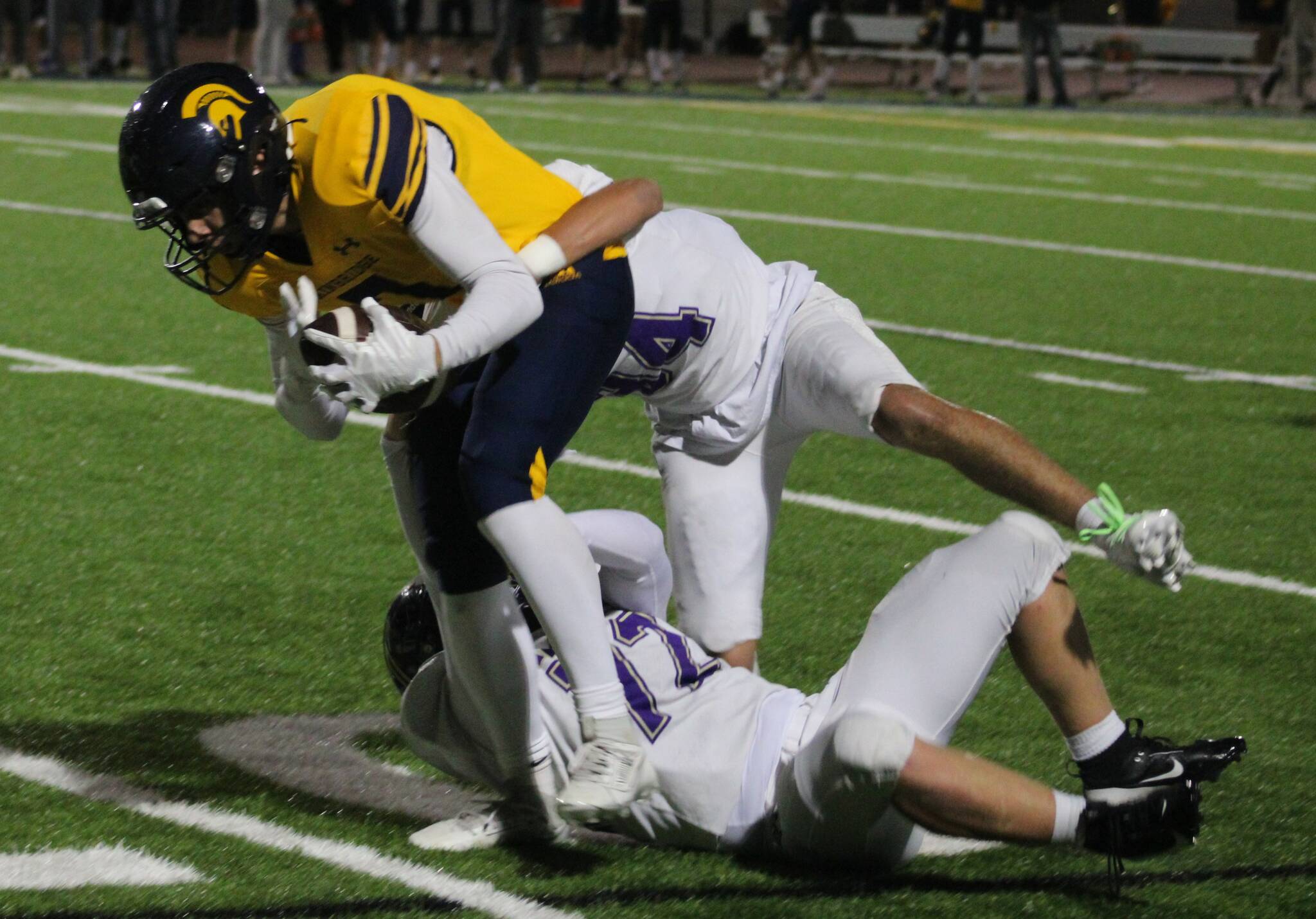 Bainbridge senior Isaiah Beyer is brought down by a pair of North Kitsap defenders.