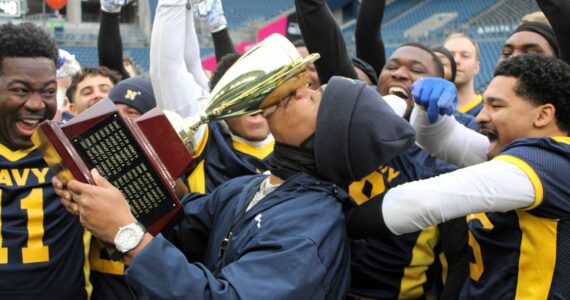 Elisha Meyer/Kitsap News Group photos
Navy coach Jason Henderson from Naval Station Everett certifies his team’s 2-0 victory over Army at Lumen Field by planting a kiss of the trophy.