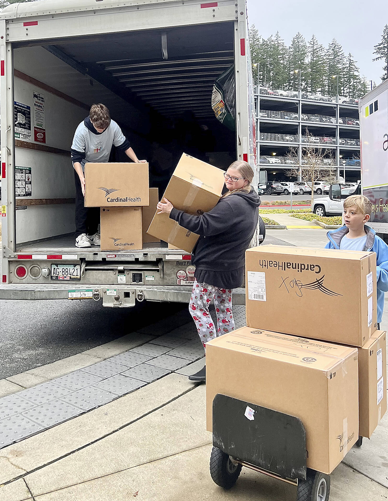 Volunteers with the nonprofit take donated boxes of toys out of a moving truck and move them inside a hospital to be given out to children.