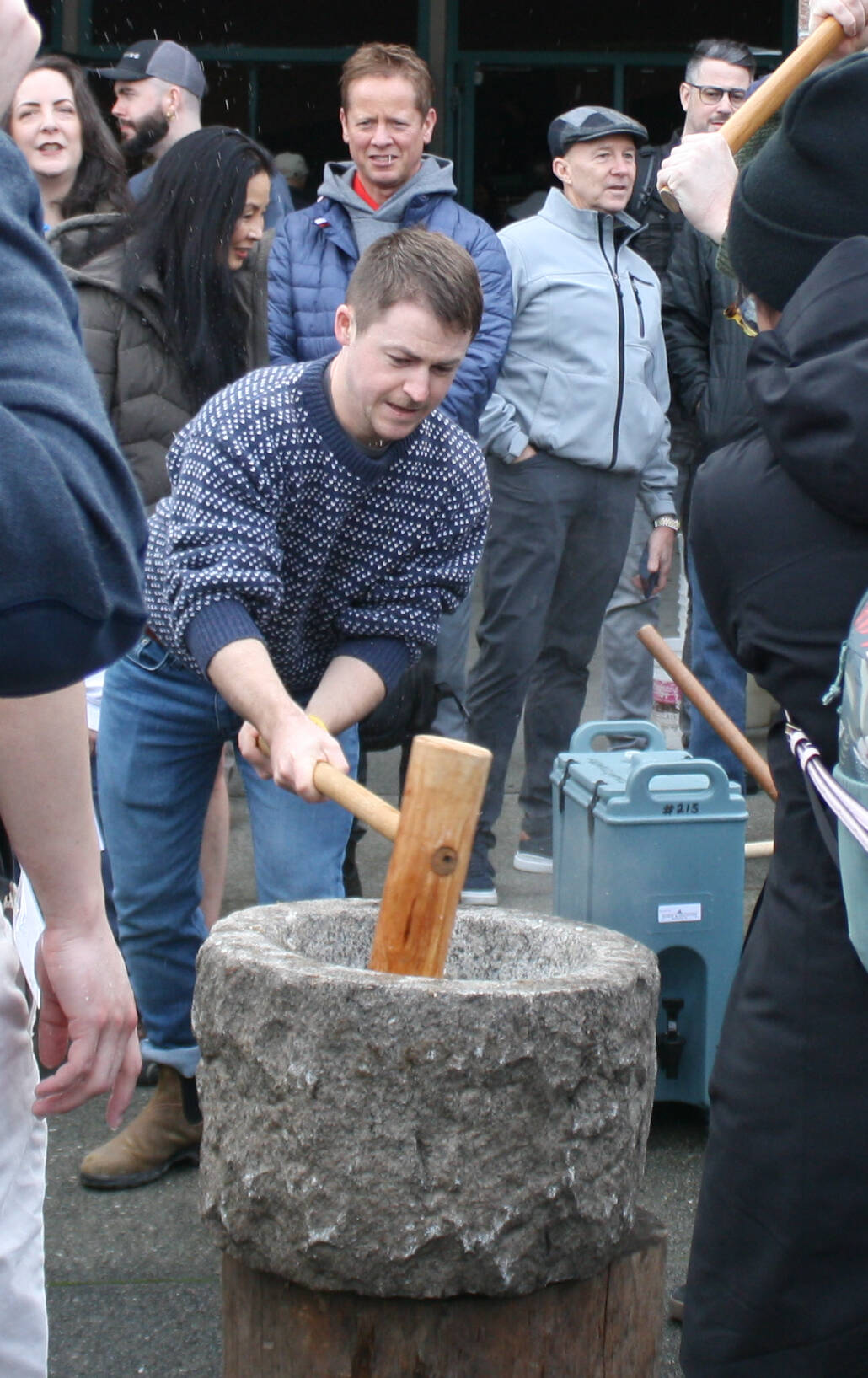 Four mochi makers take turns pounding the dough with their cherrywood kine, or mochi mallets, after the dough is taken straight from the woodstove in the usu, or stone bowl.